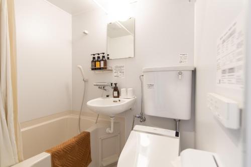 a white bathroom with a sink and a toilet at HOTEL R9 The Yard Noda in Noda