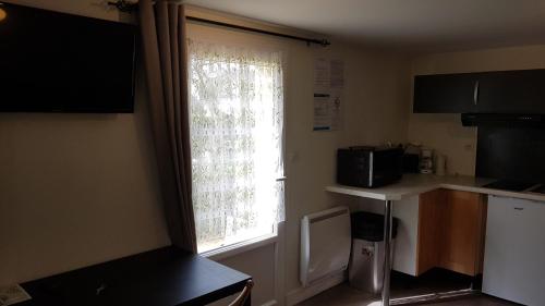 a kitchen with a window and a counter with a microwave at Les contines in Bagnoles de l'Orne