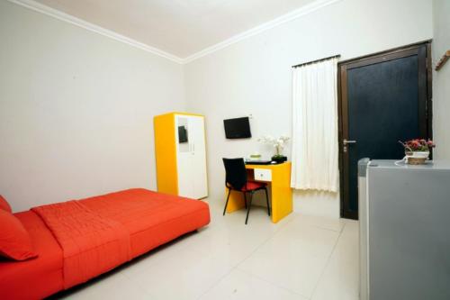 1 dormitorio con cama roja y escritorio en D'Paragon Trikora, en Palembang