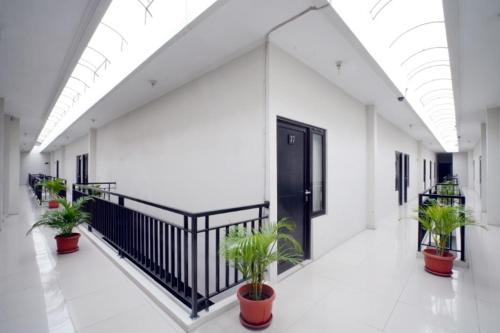 un couloir avec des plantes en pot et une porte noire dans l'établissement D'Paragon Trikora, à Palembang