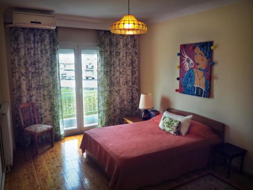 um quarto com uma cama vermelha e uma janela em Sunny apartment near the center em Tessalônica