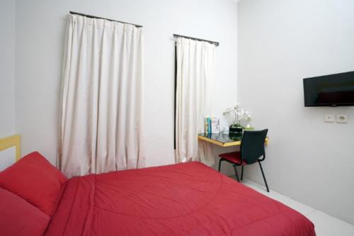 D'Paragon Pamela 1 في يوغياكارتا: غرفة نوم بسرير احمر ومكتب ونافذة