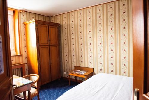 a bedroom with a bed and a cabinet and a table at Hôtel Jolly Roger in Dunkerque