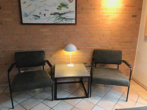 two chairs and a table with a lamp next to a brick wall at Egebjerggaard Bed & Breakfast in Sig