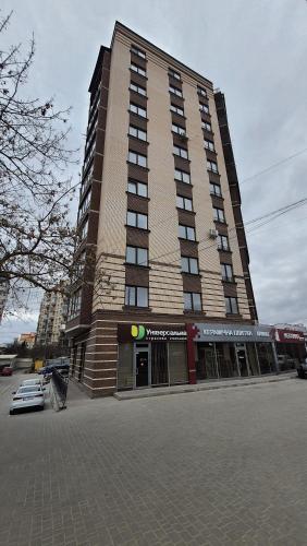 un grande edificio alto con una macchina parcheggiata di fronte di Central Apartments Апартаменти в центрі a Chmel'nyc'kyj