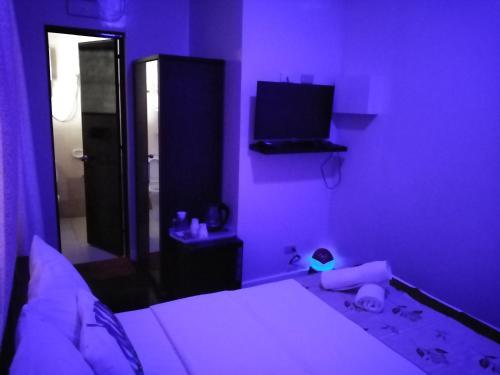 a purple bedroom with a bed and a television at HalfWay House Hostel Mactan Cebu Airport in Mactan