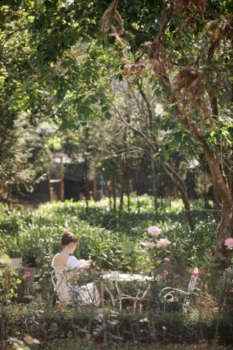 a woman sitting on a bench in a park at Dalat Terrasse Des Roses Villa in Da Lat
