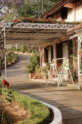 a white pergola in front of a house with flowers at Dalat Terrasse Des Roses Villa in Da Lat