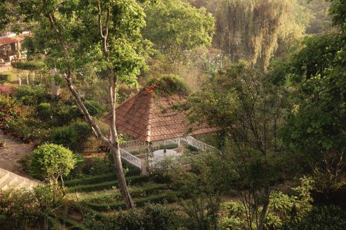 a building with a roof in a garden with trees at Dalat Terrasse Des Roses Villa in Da Lat