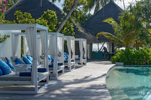 a row of lounge chairs next to a swimming pool at Constance Halaveli in Hangnaameedhoo