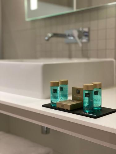 une étagère avec quatre boîtes d'odorisants sur un comptoir de salle de bains dans l'établissement Logis Hotel Relais Saint Jacques - Châteauroux, à Déols