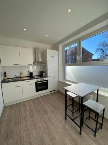 een keuken met witte kasten en een tafel en een raam bij Nordseehotel Apartments in Wilhelmshaven