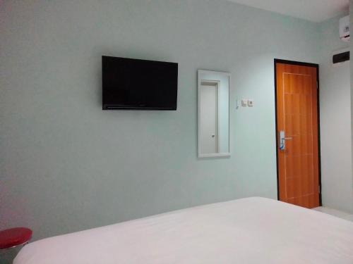 1 dormitorio con 1 cama y TV de pantalla plana en la pared en Pondok Indah24 Hotel en Yakarta