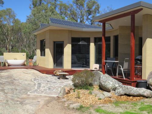 a small house with a large boulder in front of it at Earth & Soul Retreat in Cannon Creek