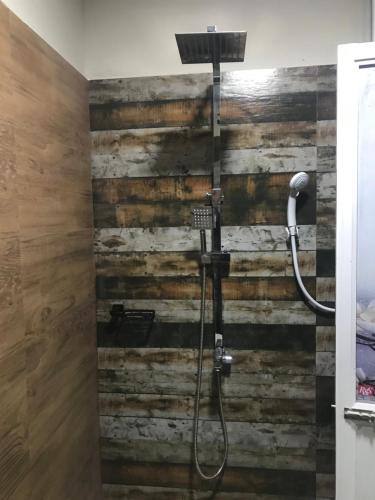 a shower in a bathroom with a wooden wall at Ceylon Resort in Wilpattu