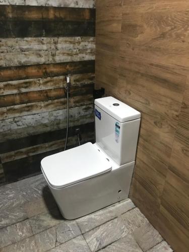 a white toilet in a bathroom with a wooden wall at Ceylon Resort in Wilpattu