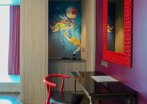 a table and a red chair in a room at Angsana Teluk Bahang, Penang in Batu Ferringhi