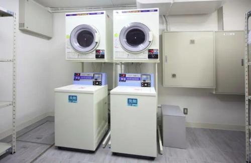 a laundry room with two washer and dryers at Exsasion Sugamo in Tokyo