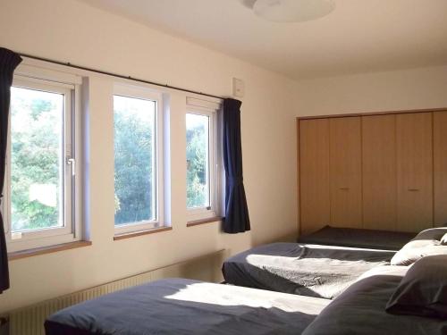 a bedroom with two beds and two windows at Pension Yu in Ebetsu