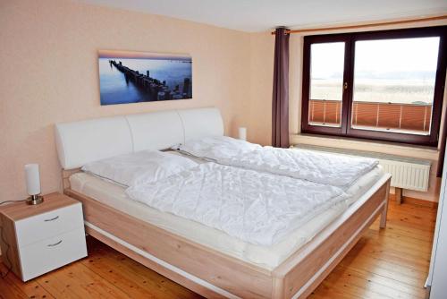 Groß ZickerにあるFerienhaus mit Reetdach und Seebliの大きな窓付きのベッドルームのベッド1台