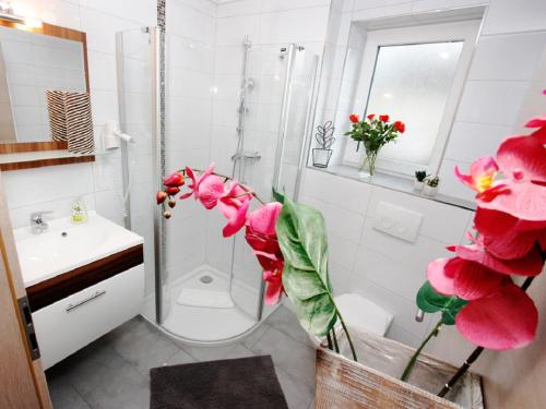 a bathroom with a shower and a toilet and flowers at Ferienwohnungen Abendsonne - 8 Gehminuten zum EP in Rust