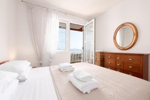 a white bedroom with a large bed and a mirror at Seaview Apartment Bosnjak Opatija in Ičići