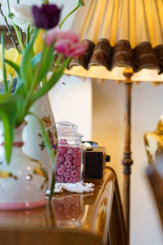 a vase with flowers on a table next to a lamp at Tante ALMA's Kölner Hotel in Cologne