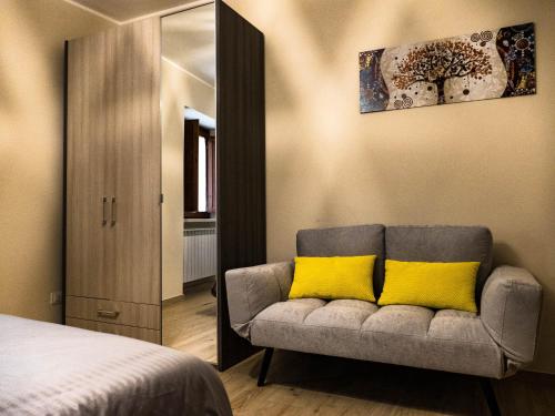 a bedroom with a couch with two yellow pillows at IL NIDO L'Aquila in LʼAquila