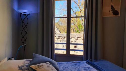 a bedroom with a bed and a window with a view at Studios du Rempart in Avignon