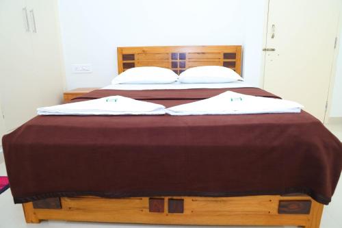 a large wooden bed with two white pillows on it at The Coorg Heaven in Madikeri