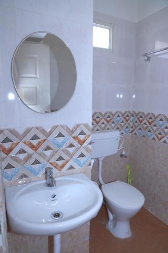 a bathroom with a sink and a toilet and a mirror at The Coorg Heaven in Madikeri