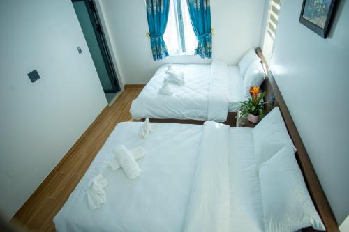 a bedroom with two beds with white sheets and a window at Win Villa Coffee in Da Lat