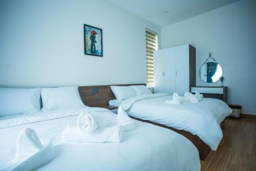 a room with three beds with white sheets at Win Villa Coffee in Da Lat
