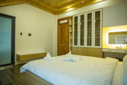 a bedroom with a large white bed and a tv at Win Villa Coffee in Da Lat