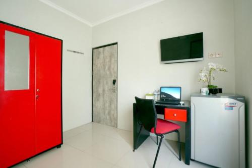 a room with a desk with a computer and a red door at D'Paragon Bukit Dieng in Malang