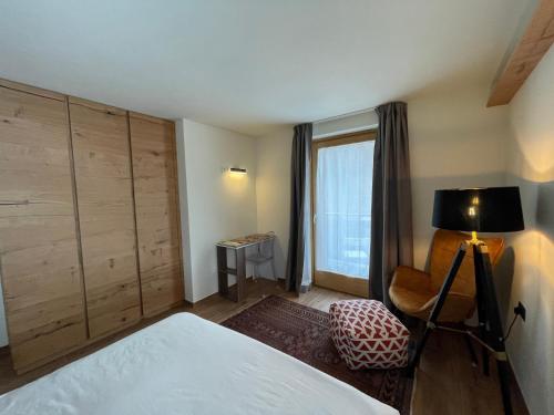 a bedroom with a bed and a chair and a window at Chalet Lilla Livigno in Livigno