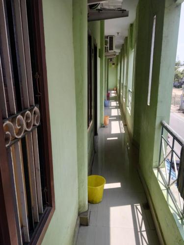 un couloir vide d'un bâtiment avec un seau jaune dans l'établissement Meera Lodge, à Chidambaram