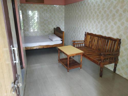 Cette chambre comprend un lit, un banc et une table. dans l'établissement Meera Lodge, à Chidambaram