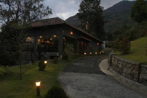 a building with lights in the grass next to a road at The Wild Trails Clarks Exotica , Munnar in Munnar