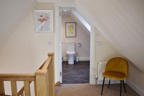a stairway with a yellow chair and a toilet at Osprey Cottage, Port o Tay in Pitlochry