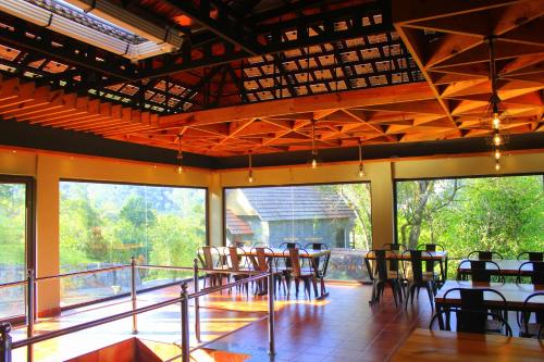 a dining room with tables and chairs and large windows at The Wild Trails Clarks Exotica , Munnar in Munnar