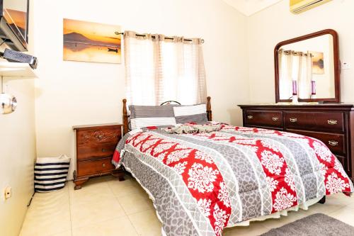 a bedroom with a bed and a dresser and a mirror at Ocho Rios Emerald 2 Bed 10 mins ocho Rios 24hrs Hot Water Wi fi in Ocho Rios