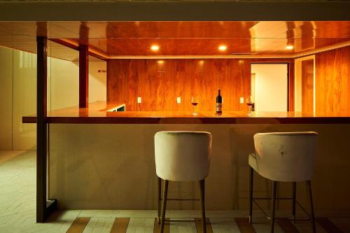 a kitchen with a bar with two white bar stools at HOTEL HIMALAYA SEA in Ito