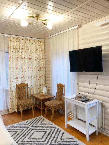 a living room with a tv and a table and chairs at Karpatska Mria in Yaremche