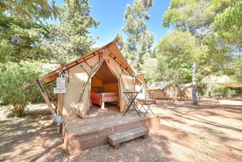 a tent with a wooden deck in a field at Salema Eco Camp - Sustainable Camping & Glamping in Salema