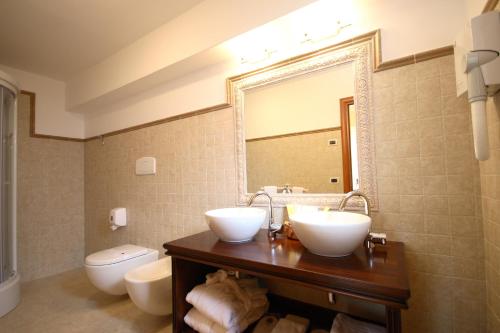 a bathroom with two sinks and a toilet and a mirror at Park Hotel Tyrrenian in Amantea