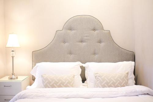 ein weißes Bett mit großem Kopfteil und zwei Kissen in der Unterkunft Classica by Kozystay - Kuningan in Jakarta