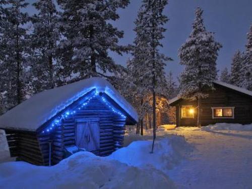 una cabaña de madera con luces azules en la nieve en Holiday Home Kuukkelitupa by Interhome, en Vuontisjärvi