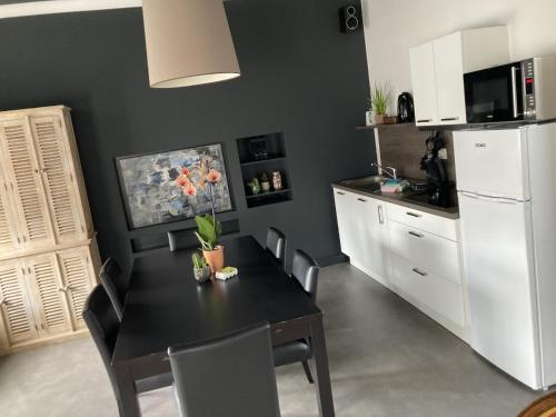 a kitchen with a black table and a white refrigerator at Gîte et Chambres d'hôte L'Amarante in Theux