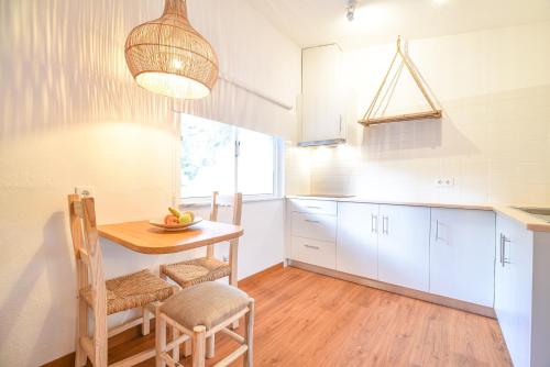 a kitchen with white cabinets and a table and chairs at Salema Eco Camp - Sustainable Camping & Glamping in Salema